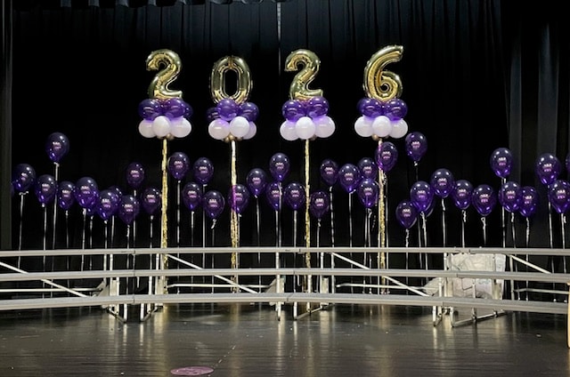 2026 graduation stage display with purple and gold balloons