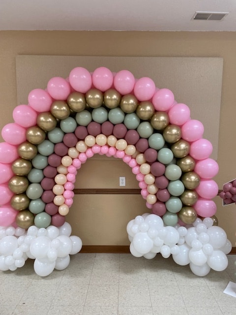 Rainbow balloon arch in pink, gold, sage, and mauve